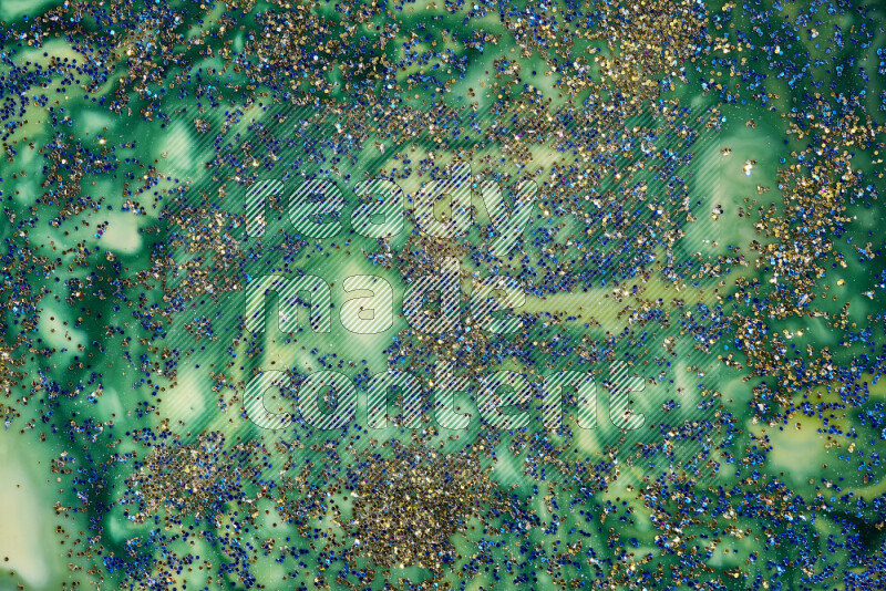 A close-up of sparkling blue glitter scattered on swirling blue and green background