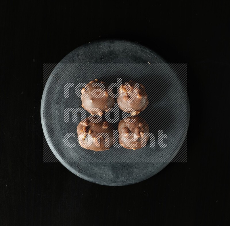 Assorted desserts in a black pottery plate on black background