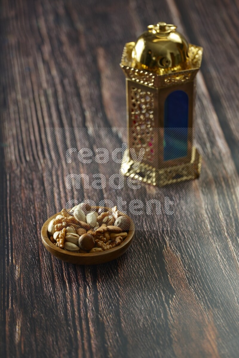 A golden lantern with different drinks, dates, nuts, prayer beads and quran on brown wooden background