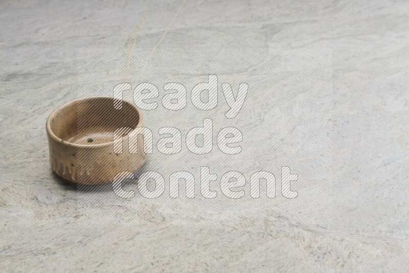 A small beige pottery bowl on grey marble background