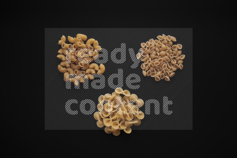 Different pasta types in bunches on black background