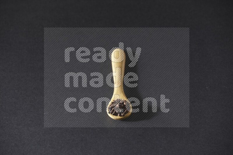 حبوب القرنفل في ملعقة خشبية علي خلفية سوداء