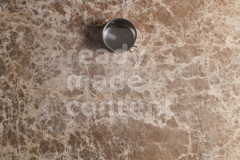 A small copper pot on beige marble background
