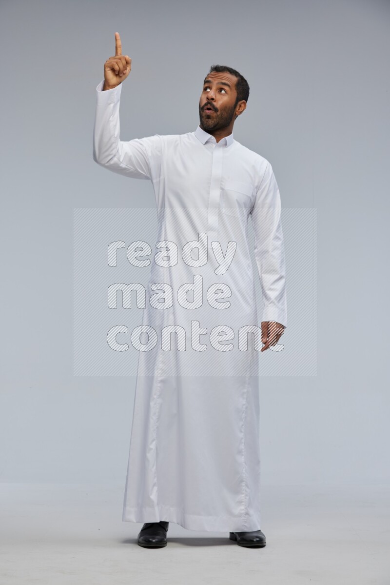 Saudi man Wearing Thob standing interacting with the camera on Gray background