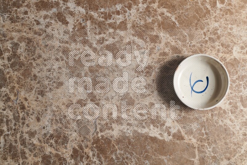 A multicolored pottery bowl on beige marble background