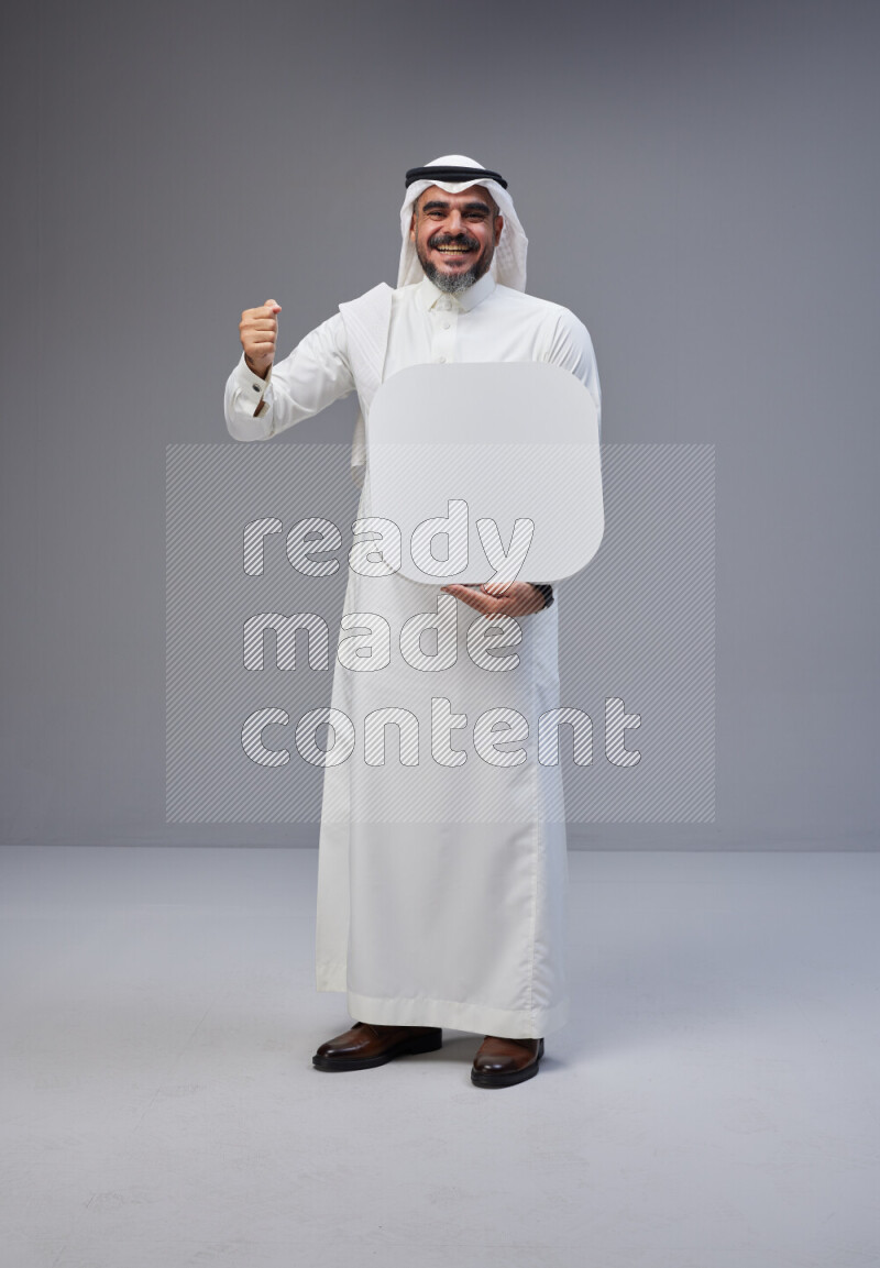 Saudi man Wearing Thob and white Shomag standing holding social media sign on Gray background