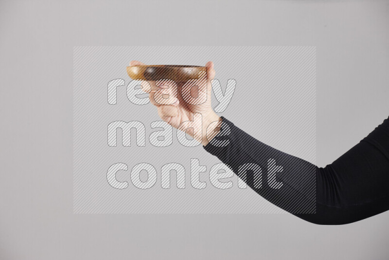 A woman in black abaya holding different wooden essentials in different positions