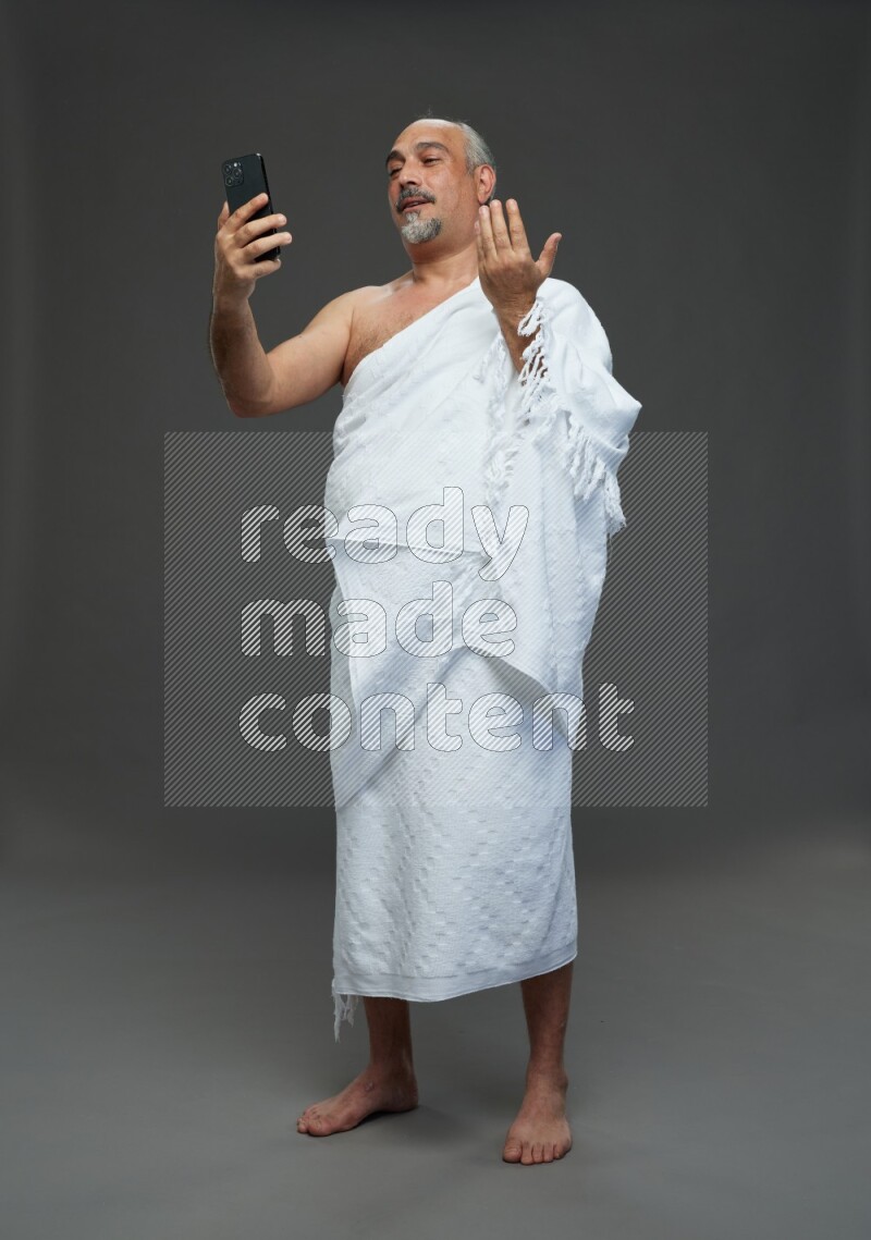 A man wearing Ehram Standing taking selfie on gray background