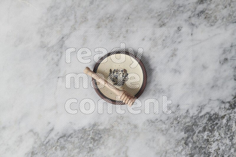 Decorative pottery plate with wooden honey dipper in it on grey marble background