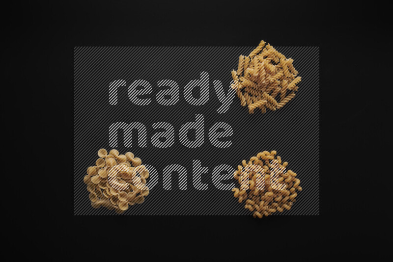 Different pasta types in bunches on black background