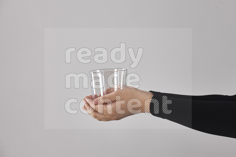 A woman in black abaya holding different glassware in different positions