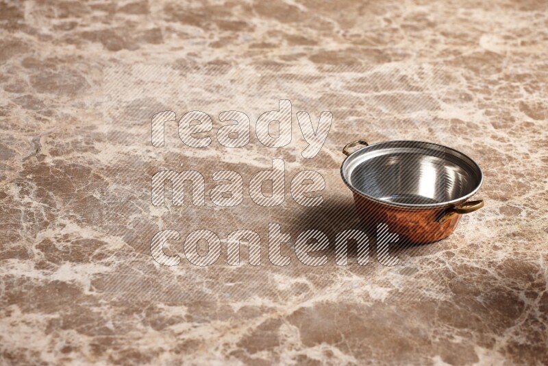 A small copper pot on beige marble background