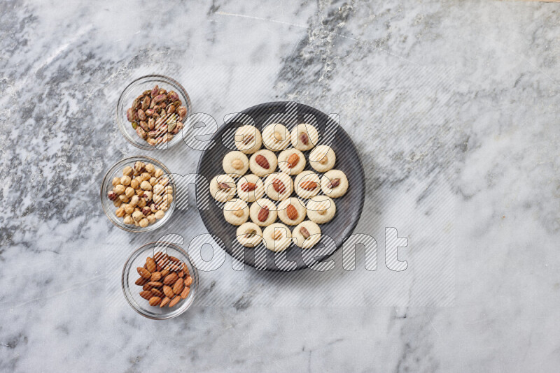 Ghoriba step by step with its ingredient, flour, powdered sugar, ghee and nuts on grey marble background