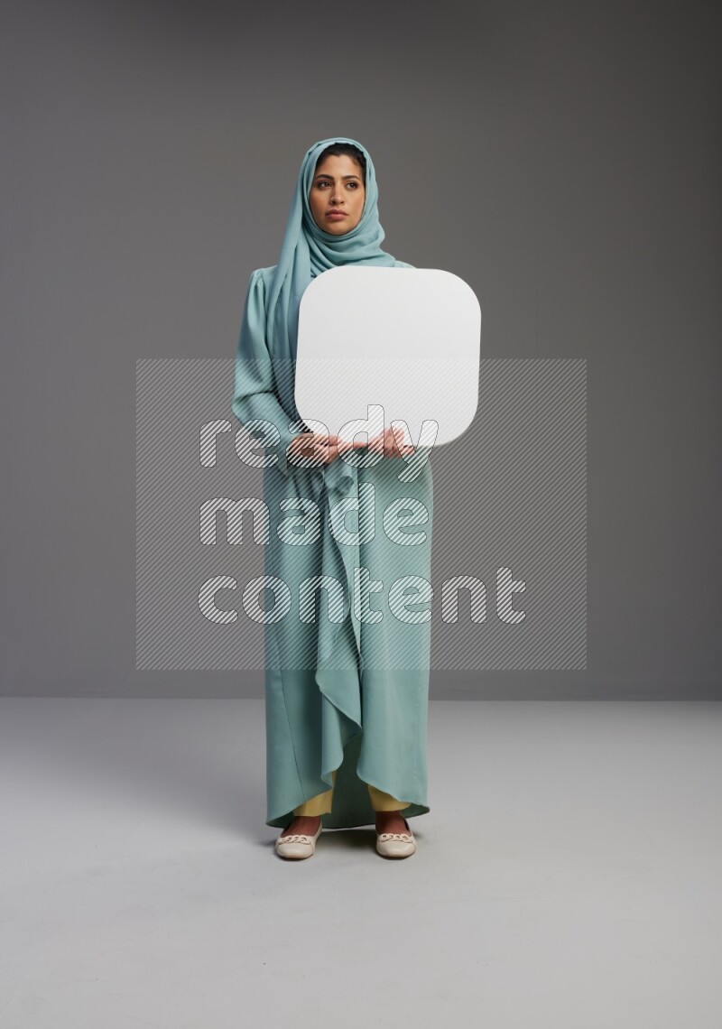 Saudi Woman wearing Abaya standing holding social media sign on Gray background