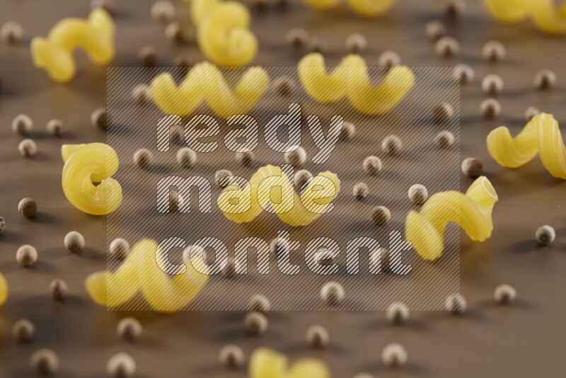 معكرونة مع مكونات متنوعة من الطماطم والثوم والبصل والفلفل الأحمر والفلفل الأسود والفلفل الأبيض وأوراق الغار وإكليل الجبل والهيل على خلفية بيج