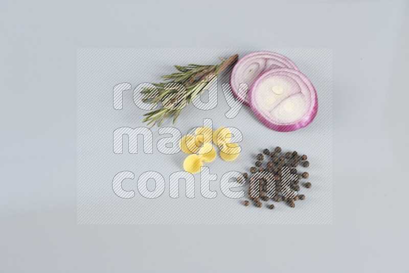 Raw pasta with different ingredients such as cherry tomatoes, garlic, onions, red chilis, black pepper, white pepper, bay laurel leaves, rosemary, cardamom and mushrooms on light blue background
