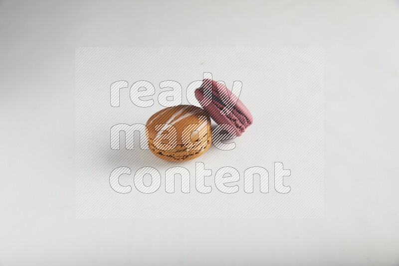 45º Shot of of two assorted Brown Irish Cream, and Red Cherry macarons on white background