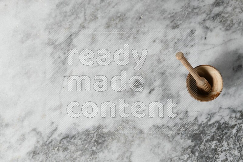 Beige pottery bowl with wooden honey dipper in it on grey marble background