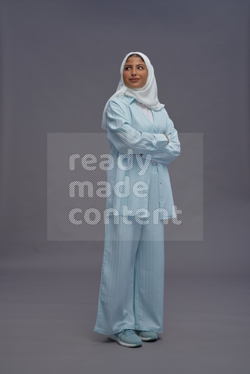 Saudi woman wearing hijab clothes standing with crossed arms on gray background