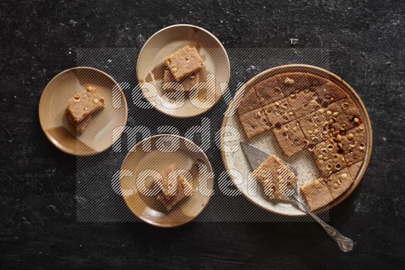 Basbousa in different plates in a dark setup