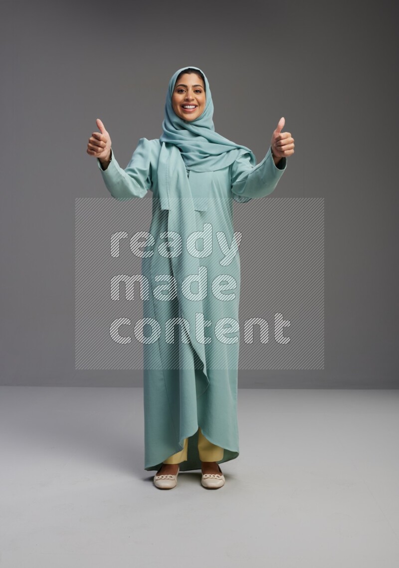 Saudi Woman wearing Abaya standing interacting with the camera on Gray background