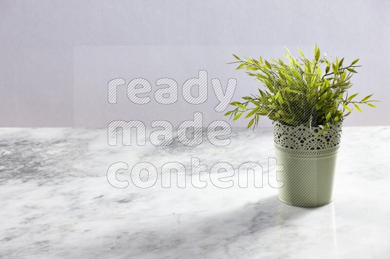 Artificial plant in green decorative pot on grey marble background