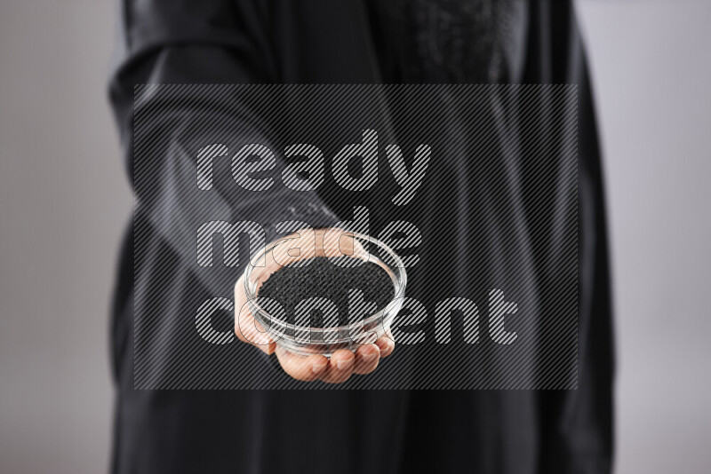Woman in abaya holding different kinds of spices in different positions
