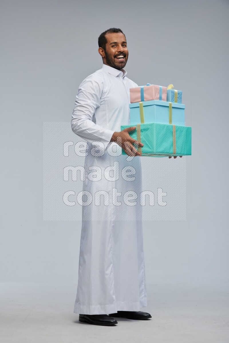Saudi man Wearing thob standing holding gift box on Gray background