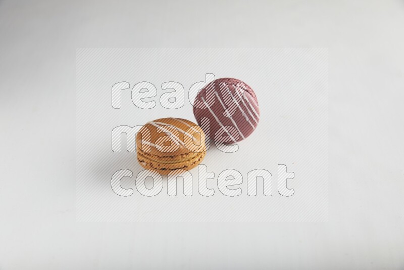 45º Shot of of two assorted Brown Irish Cream, and Red Poppy Flower macarons on white background