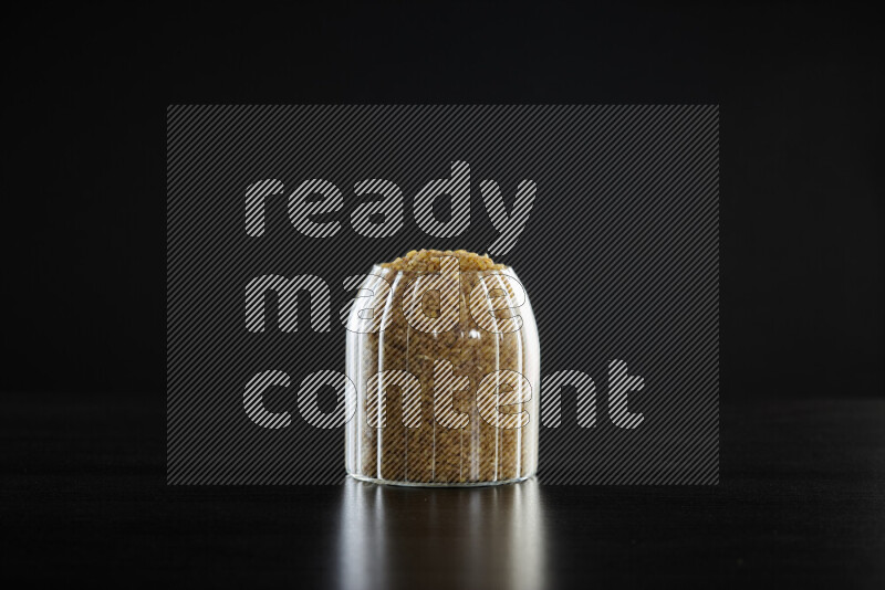 Coarse bulgur in a glass jar on black background