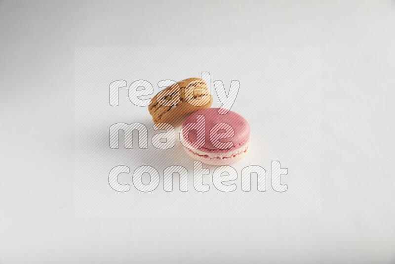 45º Shot of of two assorted Brown Irish Cream, and Pink Litchi Raspberry macarons on white background