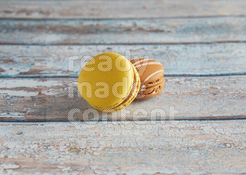 45º Shot of of two assorted Brown Irish Cream, and Yellow Lemon macarons on light blue background