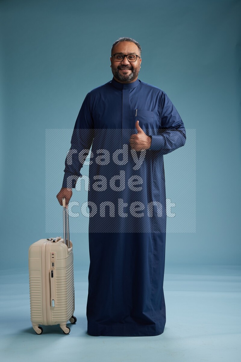 Saudi Man without shimag Standing pulling travel bag on blue background