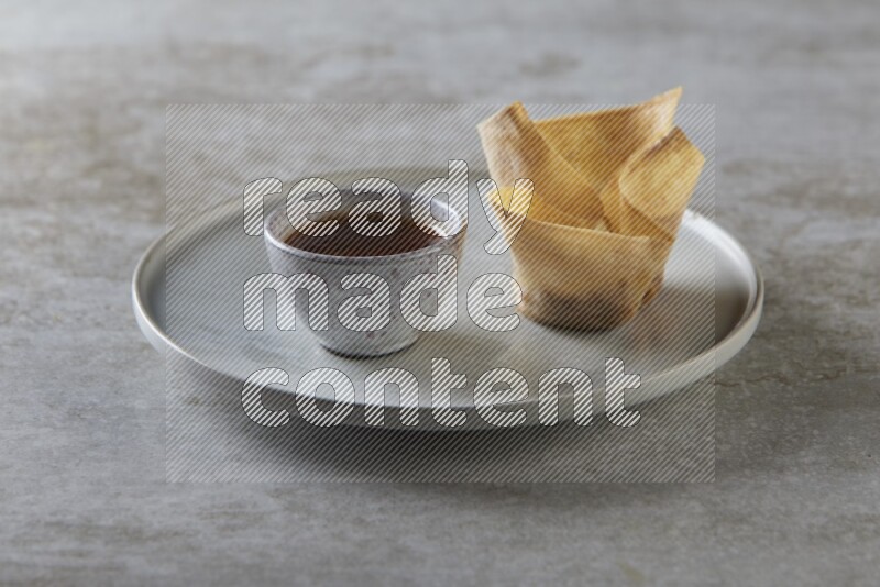 wonton cups with soy sauce ramkin on grey ceramic plate on grey textured counter top
