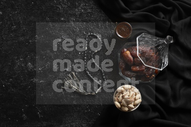 Dates in glass bowl with coffee and nuts in a dark setup