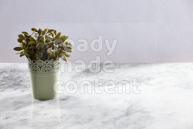 Artificial plant in green decorative pot on grey marble background