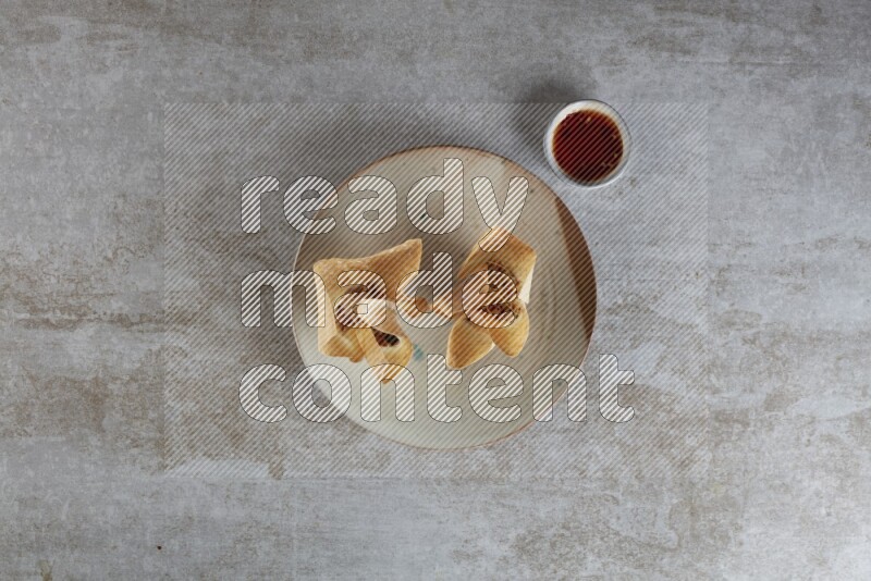 wonton cups with soy sauce ramkin on multi colored pottery on grey textured counter top