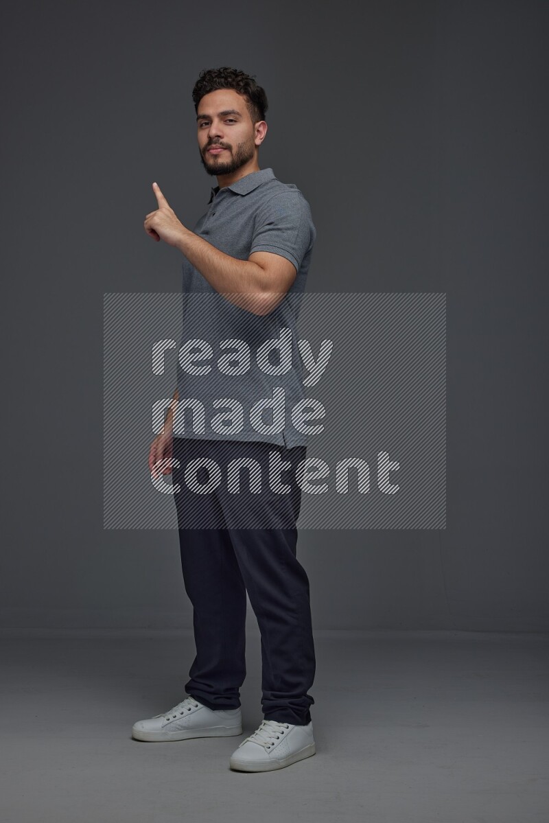 A man wearing casual standing and making multi hand gestures eye level on a gray background