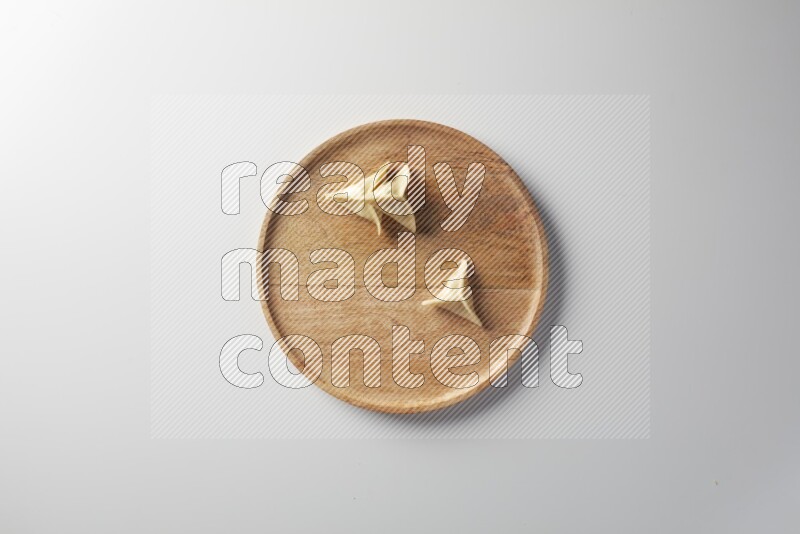 Three Sambosas on a wooden round plate on a white background