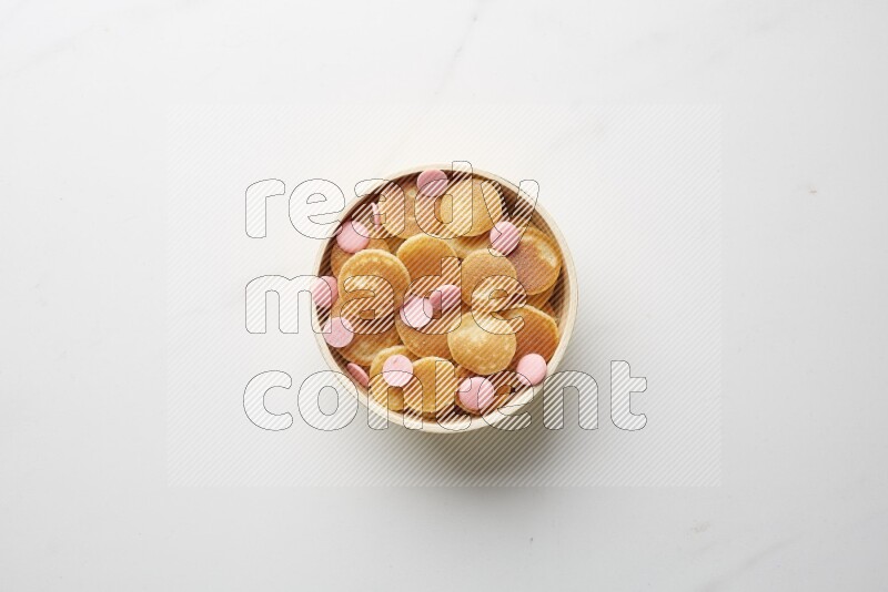 Top-view shot of pink chocolate chips cereal pancakes in a round bowl on white background