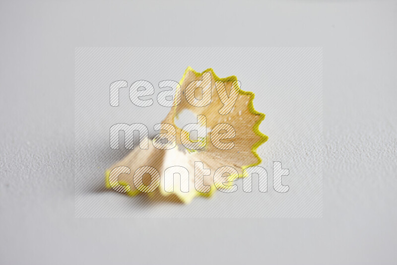 A close-up showing a small pile of pencil shavings with varied color edges on grey background