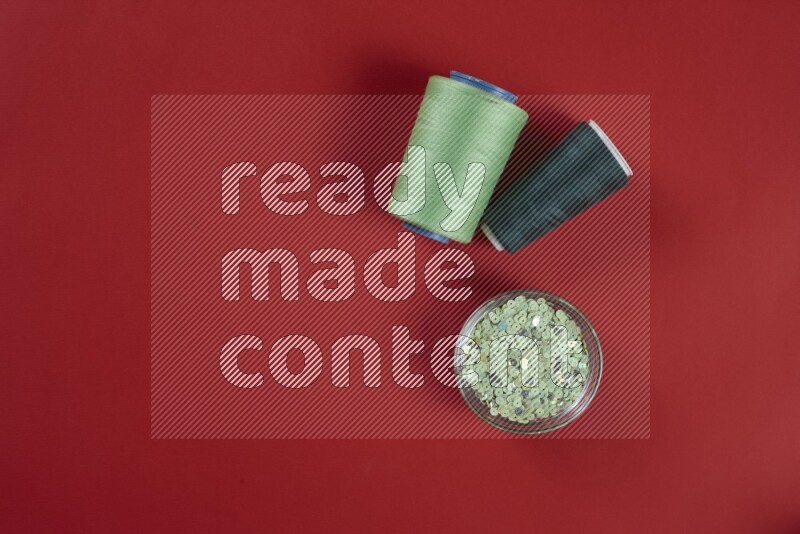 A green and red collection of sewing and tailoring tools arranged on a red background