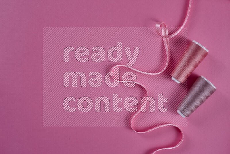 A pink collection of sewing and tailoring tools arranged on a pink background