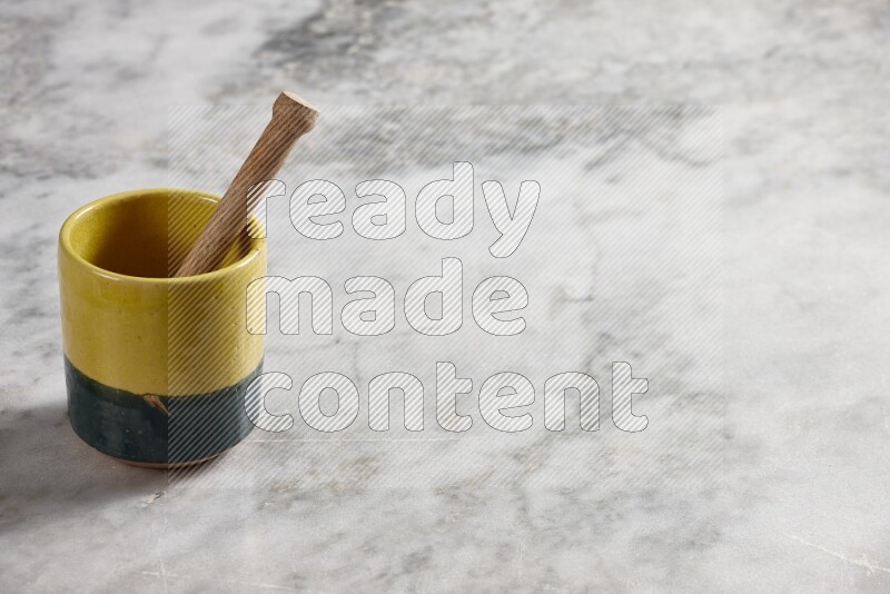 Multicolored pottery cup with wooden honey dipper in it on grey marble background