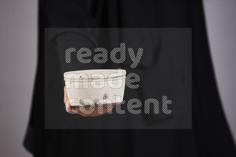 امرأة ترتدي عباءة سوداء تحمل أدوات فخارية مختلفة في أوضاع متعددة