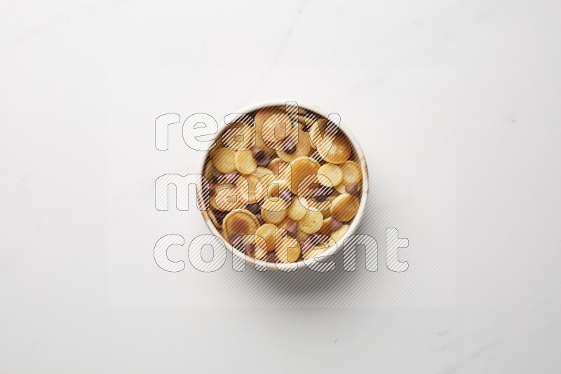 Top-view shot of chocolate chips cereal pancakes in a round bowl on white background
