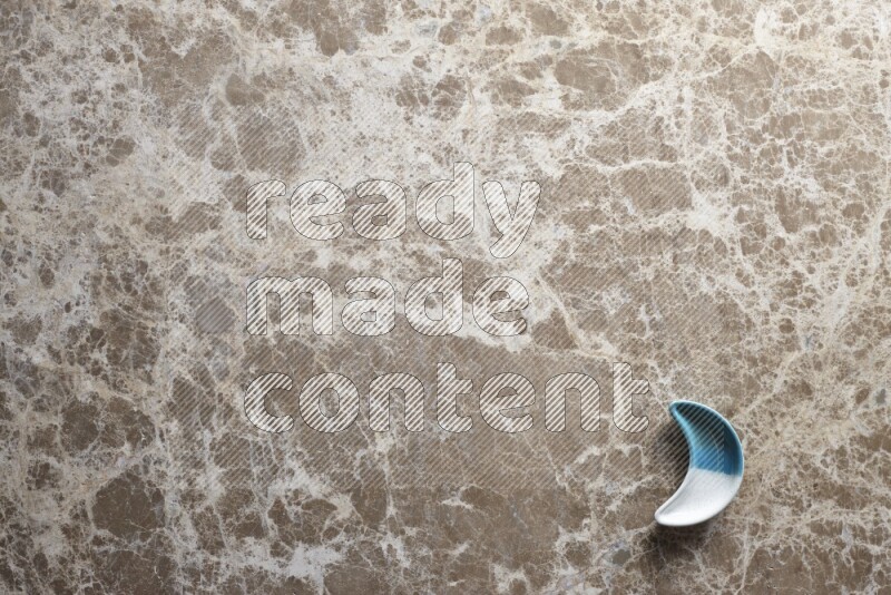 A pottery crescent plate on beige marble background