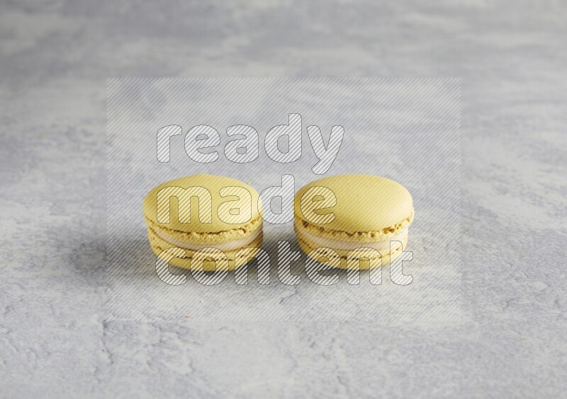 45º Shot of two Yellow Lime macarons  on white  marble background