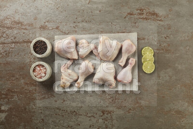 Mixed fresh chicken pieces on a parchment paper direct on a textured rustic background