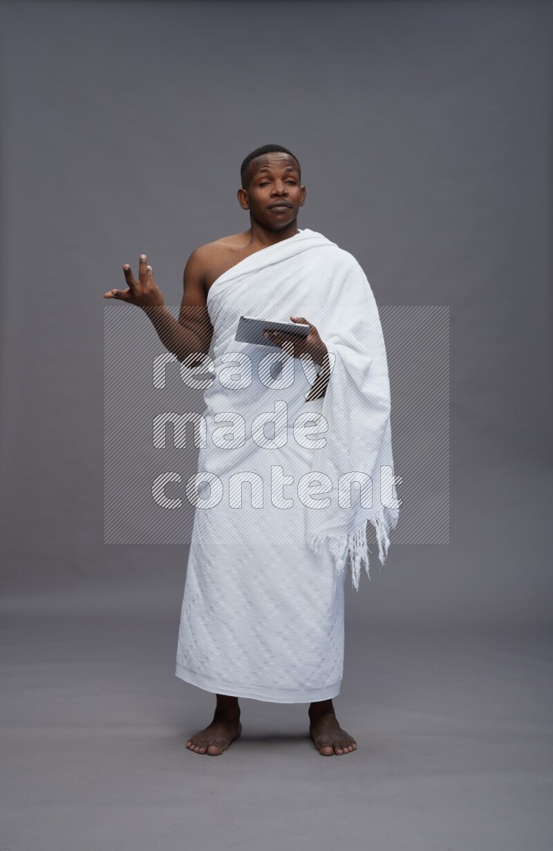 A man wearing Ehram Standing working on tablet on gray background